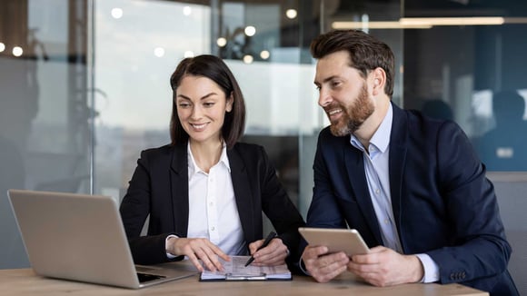 Twee adviseurs kijken naar informatie op laptop